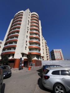 a tall building with cars parked in a parking lot at Apartments Lux Palas in Iaşi