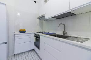 a white kitchen with a sink and a stove at Al Ciglio Holiday House Amalfi Coast in Scala