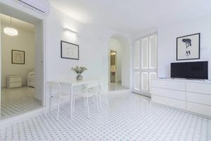 a white dining room with a table and a tv at Al Ciglio Holiday House Amalfi Coast in Scala