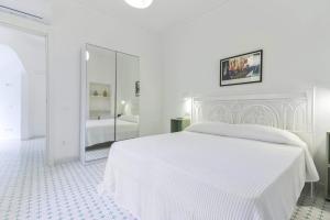 a white bedroom with a white bed and a mirror at Al Ciglio Holiday House Amalfi Coast in Scala