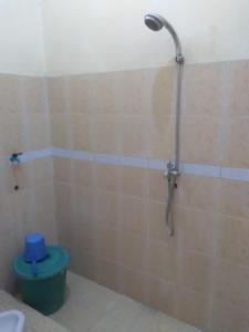 um chuveiro na casa de banho com uma lata de lixo verde em House 08 em Pekalongan