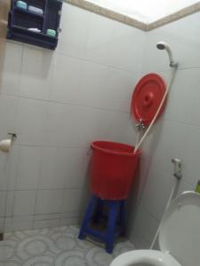 a red bucket in a bathroom with a toilet at House 08 in Pekalongan