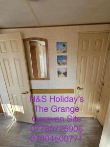 a room with two doors and a mirror at H&S Holidays in Addlethorpe +2 photos