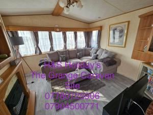 a living room with a couch and a tv at H&S Holidays in Addlethorpe