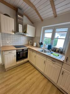 a kitchen with white cabinets and a sink at Ferienhaus Lillehus in Fehmarn
