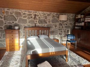1 dormitorio con cama y pared de piedra en Casa das Castanhas - near Gerês en Braga