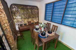 a dining room with tables and chairs and windows at Diani Luxury 2 bedroom Villa in Magutu