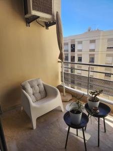 a living room with a white chair and a balcony at Chez Dju in Nouaceur