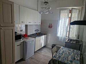 eine Küche mit weißen Schränken, einer Spüle und einem Tisch in der Unterkunft Partenope in Levanto