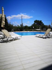 - un ensemble de chaises longues installées à côté de la piscine dans l'établissement 3 Island View Hotel, à Nydri