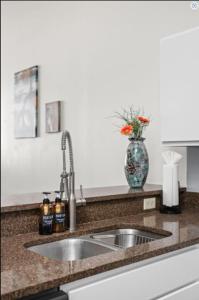 a kitchen counter with a sink and a vase with flowers at CozySuites - 2BR with Direct Skybridge Access #6 in Indianapolis