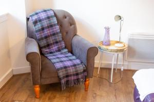 a chair with a plaid blanket sitting next to a table at 5 wheelhouse apartments in Lochinver