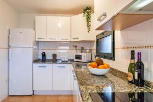 a kitchen with white cabinets and a bowl of fruit on a counter at Sunrise Surf House, Big Garden, Hot Tub, Parking, super-fast free Wi-Fi in Corralejo
