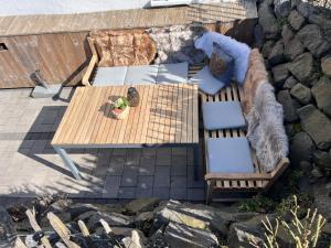 a wooden table and chairs on a patio with rocks at Eifelferienhaus An der Kapelle - kostenlose Sauna, Ofen in Kerschenbach