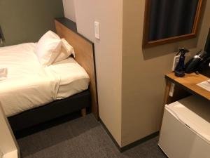 Habitación de hotel con cama y escritorio con teléfono en Kamon Hotel Seto, en Hiroshima