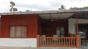 ein kleines Haus mit einer Holzveranda und einer Veranda in der Unterkunft Homestay Bonda Azizah 11-13pax in Kota