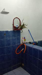 eine Dusche mit orangefarbenem Schlauch an einer blauen Kachelwand in der Unterkunft Homestay Bonda Azizah 11-13pax in Kota
