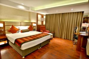een hotelkamer met een groot bed en een stoel bij Regenta Central the Crystal Kanpur, in Kānpur