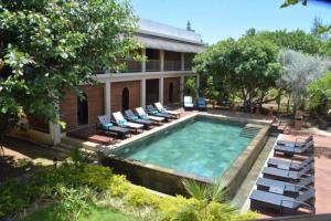 a swimming pool with lounge chairs and a building at Garden lodge in Pereybere