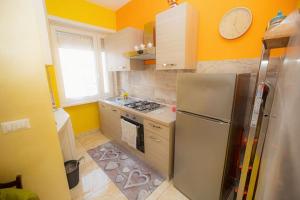 a kitchen with yellow walls and a stainless steel refrigerator at Appartamento La Coccinella in Lido di Ostia +9 photos