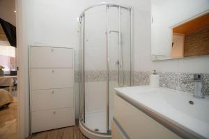 baño blanco con ducha y lavamanos en Appartamento La Coccinella, en Lido di Ostia