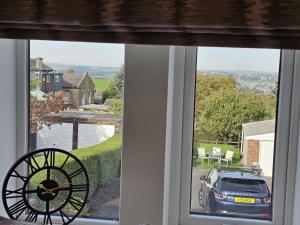 a window with a view of a car parked in a driveway at Hop Cottage in Mirfield