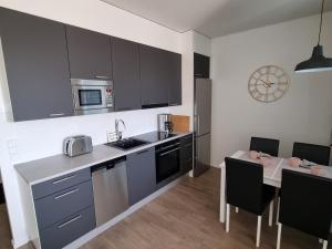 a kitchen with gray cabinets and a table with chairs at Upea huoneisto Rauman keskustassa in Rauma