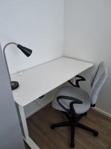 a white desk with a chair and a lamp at Upea huoneisto Rauman keskustassa in Rauma