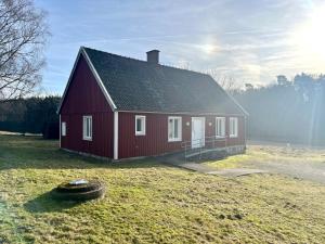 Uma casa vermelha com um pneu à frente. em Jocksborg - Country side cottage in the woods em Sjöbo