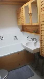 uma casa de banho com um lavatório branco e armários de madeira em Superbe studio aux 7 Laux em La Ferrière