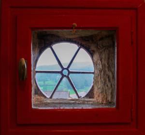 una ventana en una puerta roja con vistas en Pannonica charmante maison champêtre, en Montagny-sur-Grosne