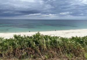 a beach with people walking on the sand and the ocean at APARTAMENTO A ESTRENAR en FOZ COFRADIA DELUXE in Foz