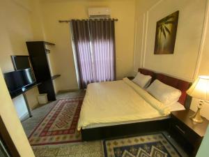 The 1st Night Hotel في عمّان: غرفة نوم صغيرة بها سرير وتلفزيون