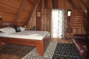ein Schlafzimmer mit einem Bett und einem Sofa in einer Hütte in der Unterkunft KSW BASE NAUTIQUE Isonalambo in Kribi