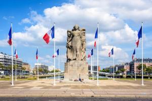 Uma estátua numa praça com bandeiras à volta. em Échappée mer LH em Le Havre