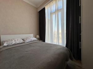 um quarto com uma cama e uma grande janela em Apartment 45 em Tbilisi