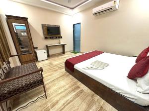 1 dormitorio con 1 cama, 1 silla y TV en Hotel Kelson Dx, en Nueva Delhi