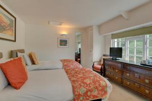 1 dormitorio con 1 cama y vestidor con TV en The Crown Hotel, en Exford