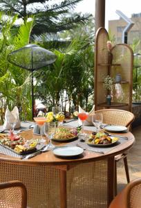 une table en bois avec des assiettes de nourriture dans l'établissement URBANE BY TREAT, à Daman