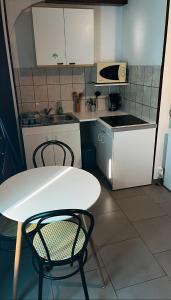 la chambre de Jade في Hirson: مطبخ صغير مع طاولة بيضاء وكراسي