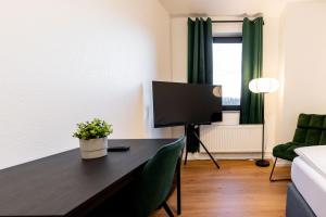 a living room with a table and a tv at Dream Factory by Hotel Bergheim in Bergheim
