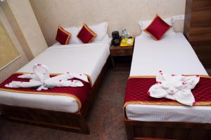 two beds in a room with towels on them at Sri Vishnu Residency in Sriperumbudur