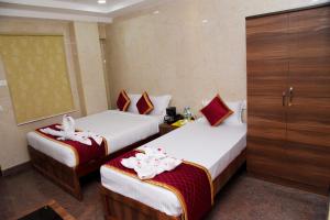 two beds in a hotel room with towels on them at Sri Vishnu Residency in Sriperumbudur