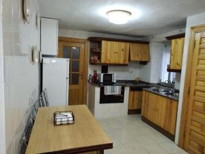 een keuken met een houten tafel en een witte koelkast bij Casa Josefa in Villasuso de Cieza