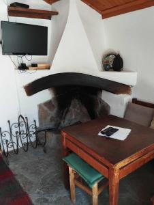 ein Wohnzimmer mit einem Tisch und einem Kamin in der Unterkunft Расимова къща in Bozhentsi + 17 Fotos