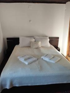 a bed with two towels on top of it at Расимова къща in Bozhentsi
