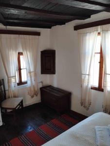 um quarto com uma cama, uma cómoda e janelas em Расимова къща em Bozhentsi