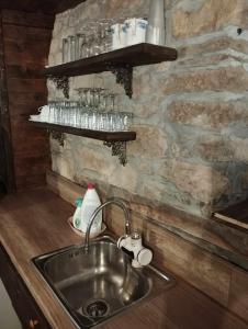 eine Küche mit einem Waschbecken und einer Steinmauer in der Unterkunft Расимова къща in Bozhentsi