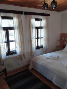 um quarto com uma cama e duas janelas em Расимова къща em Bozhentsi