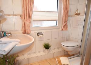 ein Bad mit einem Waschbecken, einem WC und einem Fenster in der Unterkunft Dünenstübchen Baltrum in Baltrum
